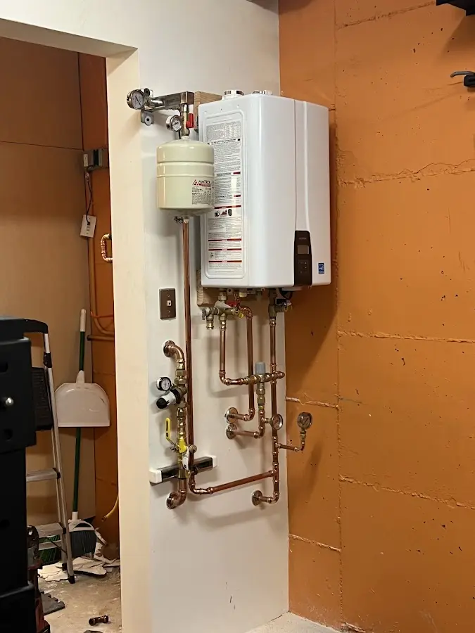Plumbing technician inspecting water heater connections in Waterville